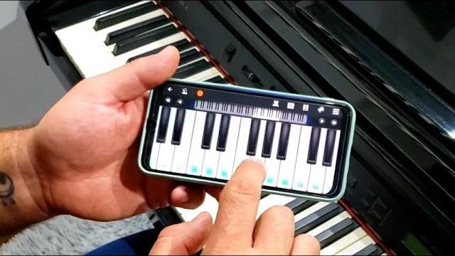 A modern smartphone displaying a piano learning app interface, prominently featured in the foreground with a user’s hands engaged on the touchscreen, tapping on musical notes. The middle ground includes a sleek, minimalistic piano with glossy black and white keys, reflecting soft ambient light. In the background, an inviting and cozy living room set up with a large window, letting in warm sunlight, casting gentle shadows on the floor. The overall atmosphere is focused and serene, ideal for learning, with a setup suggesting both technology and musicality. Elements like a notebook and a cup of coffee placed beside the piano add a personal touch to the scene. The lighting is soft and diffused, giving a calm, inspiring mood.