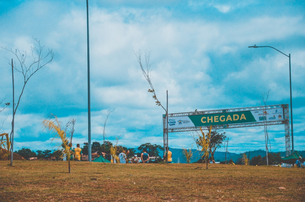 a group of people standing in a field next to a sign — Foto por Hector Brasil na Unsplash