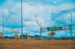 a group of people standing in a field next to a sign — Foto por Hector Brasil na Unsplash